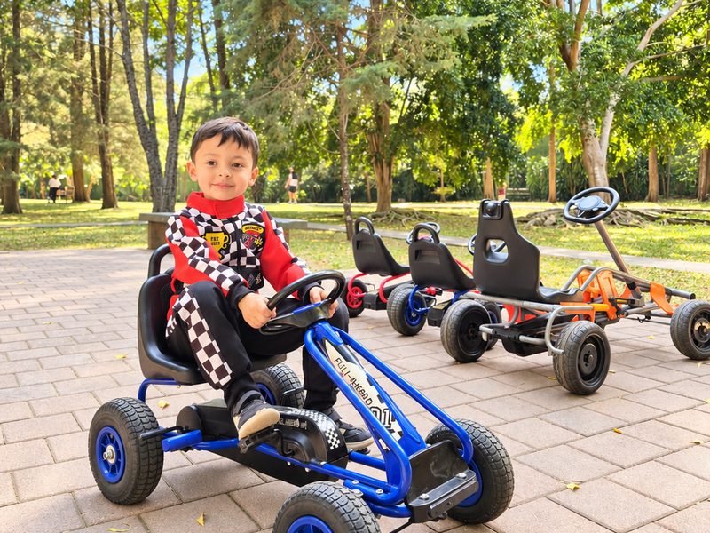 Niño con traje de piloto listo en su kart azul